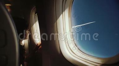 可爱有趣的小孩在飞行时看着窗户。 坐在靠近窗户的座位上，阳光透过窗户照射进来